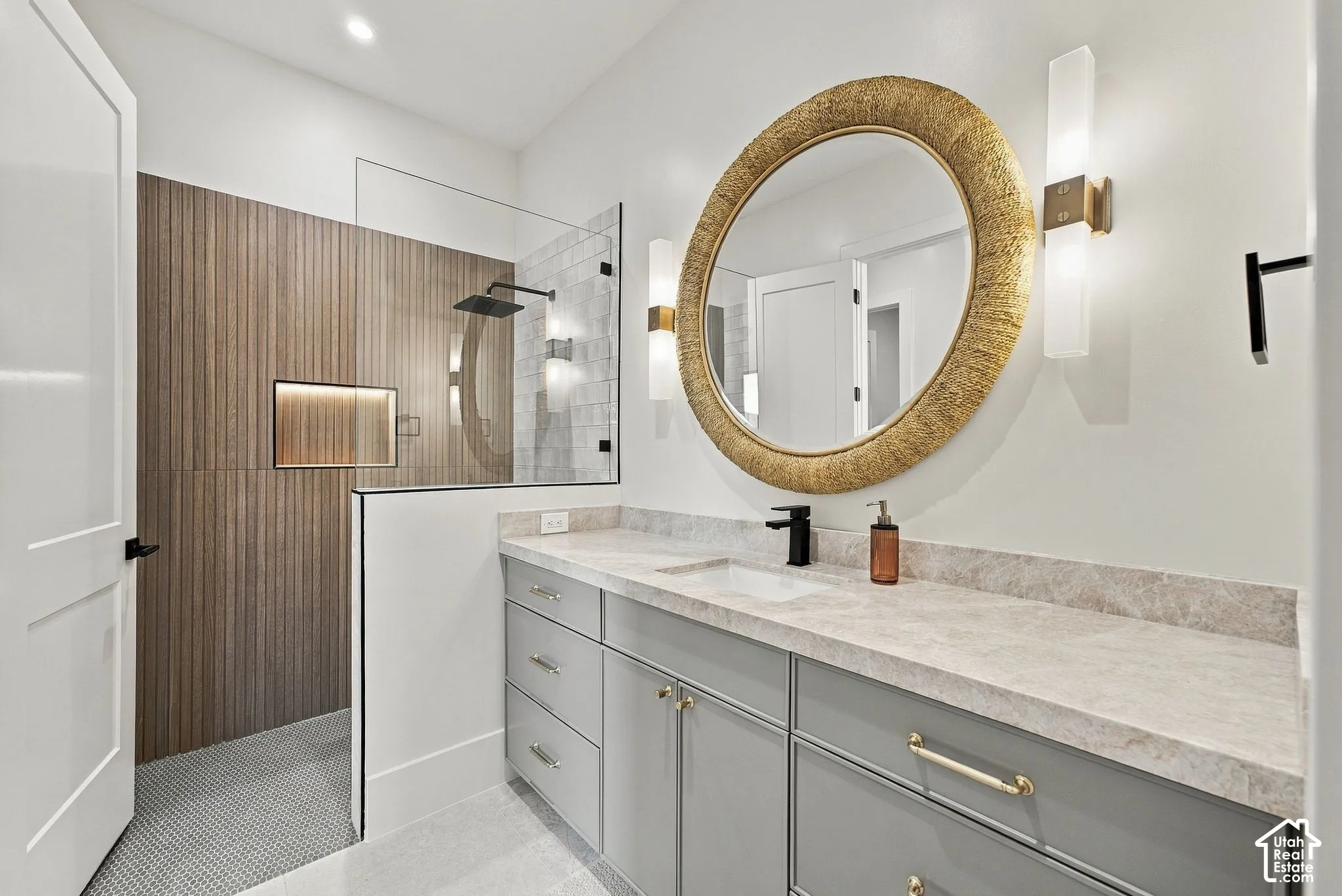 Bathroom featuring a dual-sink vanity with stone countertop, wood-finish wall paneling, walk-in shower with glass enclosure, and matte black fixtures