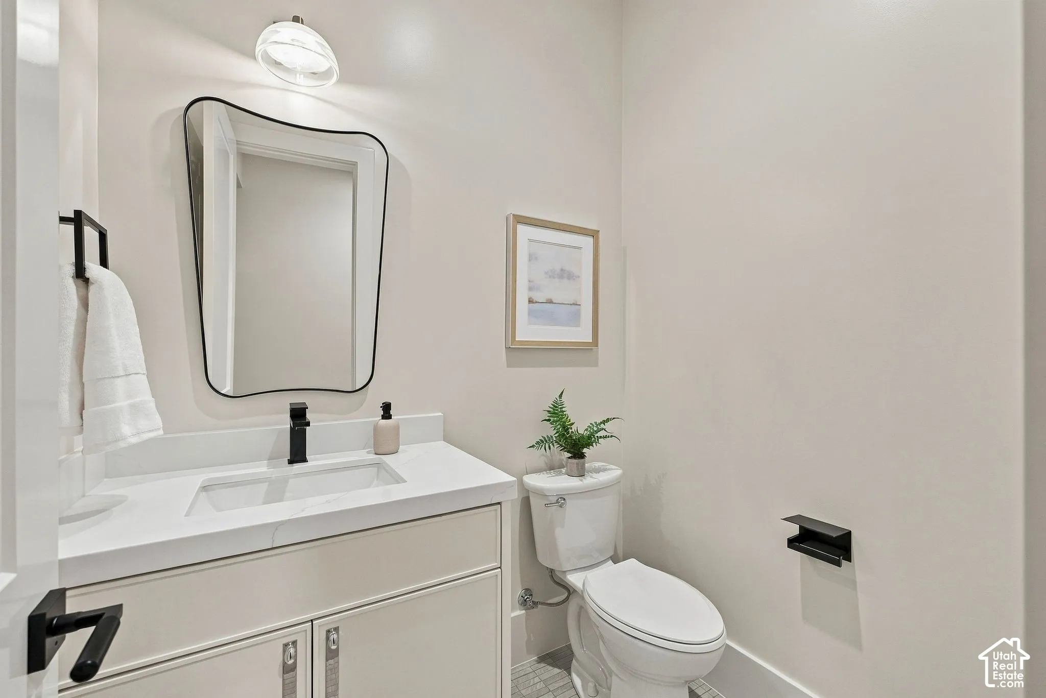 Vanity featuring a solid-surface countertop with an integrated rectangular sink and matte black faucet, paired with an asymmetrical wall-mounted mirror and matching matte black hardware