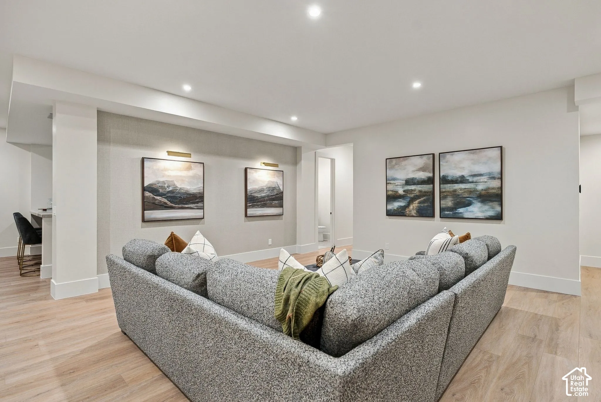 Spacious room featuring wood-finish flooring, recessed lighting, and wall-mounted picture lights