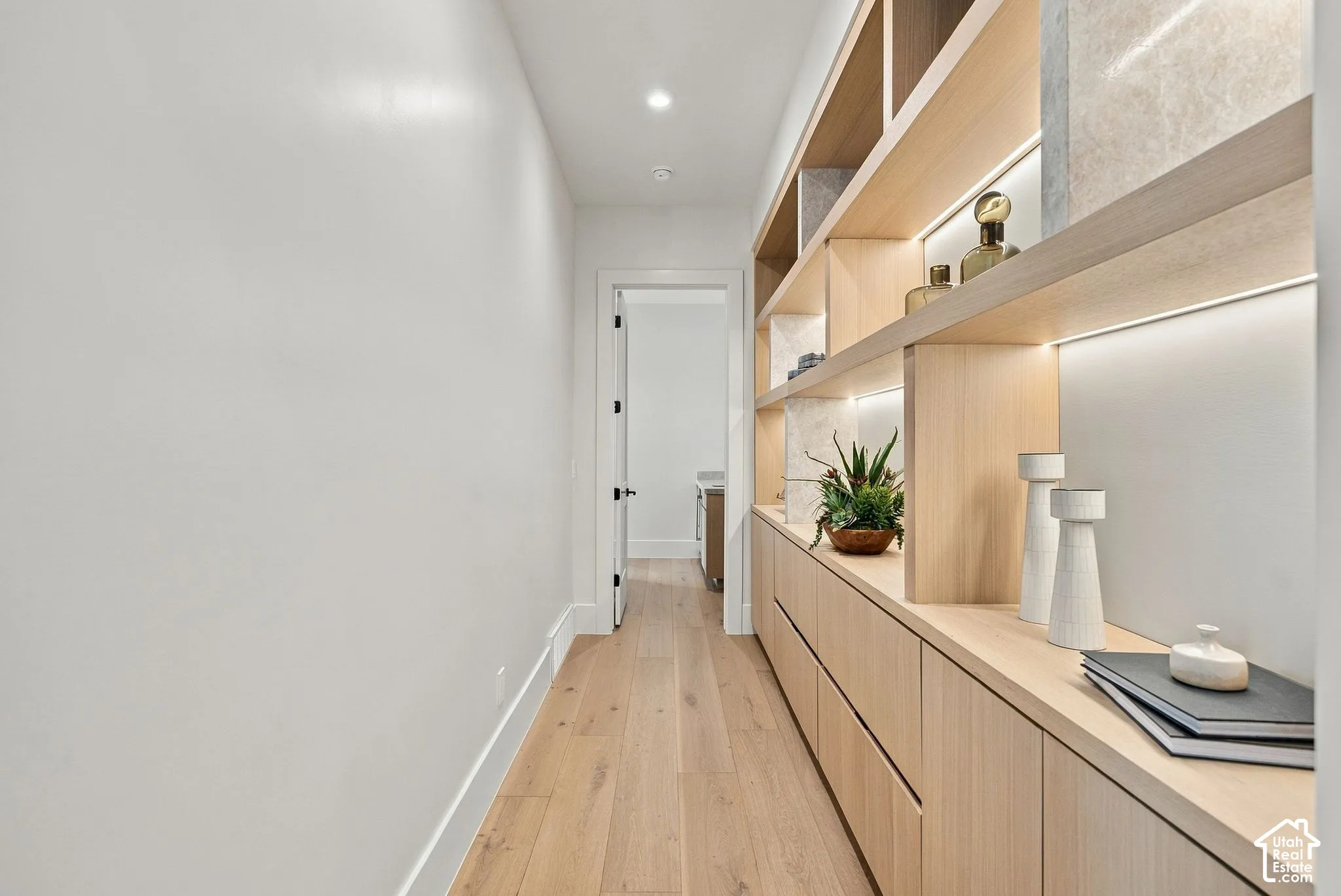 Custom floor-to-ceiling cabinetry with integrated LED lighting, open shelving, and wood-finish flooring