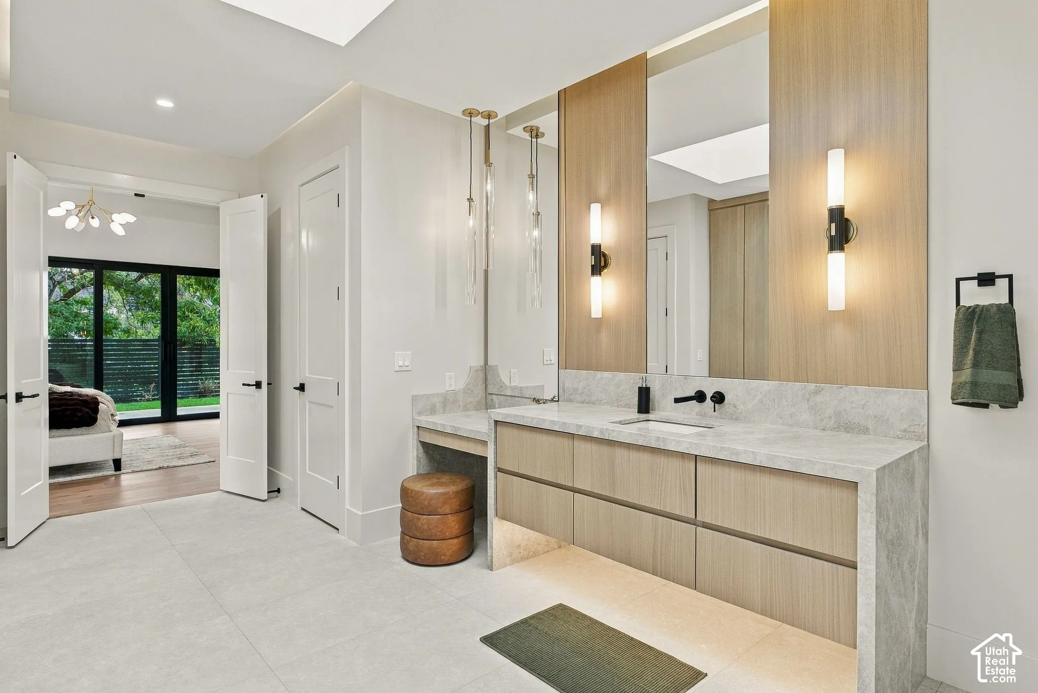 Bathroom featuring a floating vanity with wood-finish cabinetry, stone countertop, dual wall-mounted sconces, and matte black plumbing fixtures