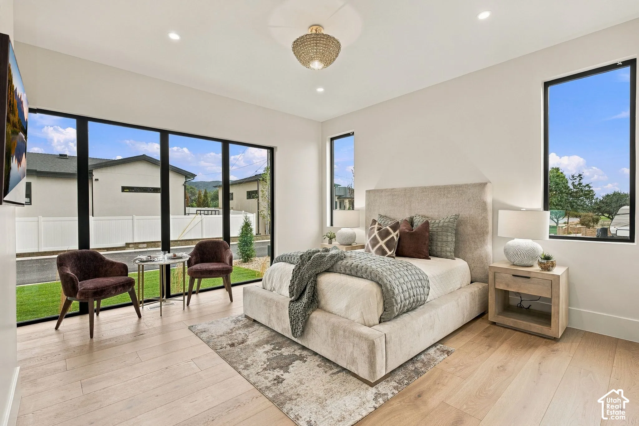 Spacious room featuring floor-to-ceiling windows with black frames, wood-finish flooring, recessed lighting, and a decorative ceiling fixture
