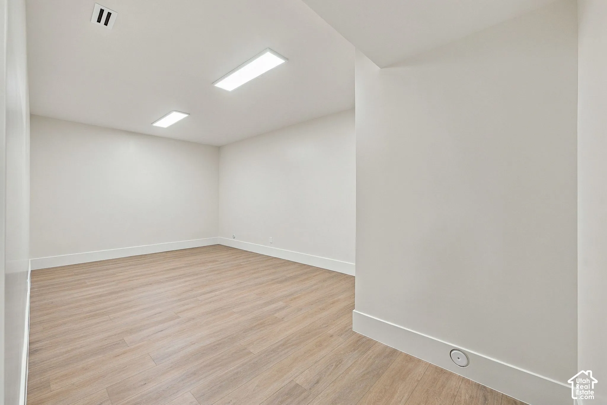 Neutral-toned interior space featuring wood-finish flooring, recessed lighting, and smooth-finish walls
