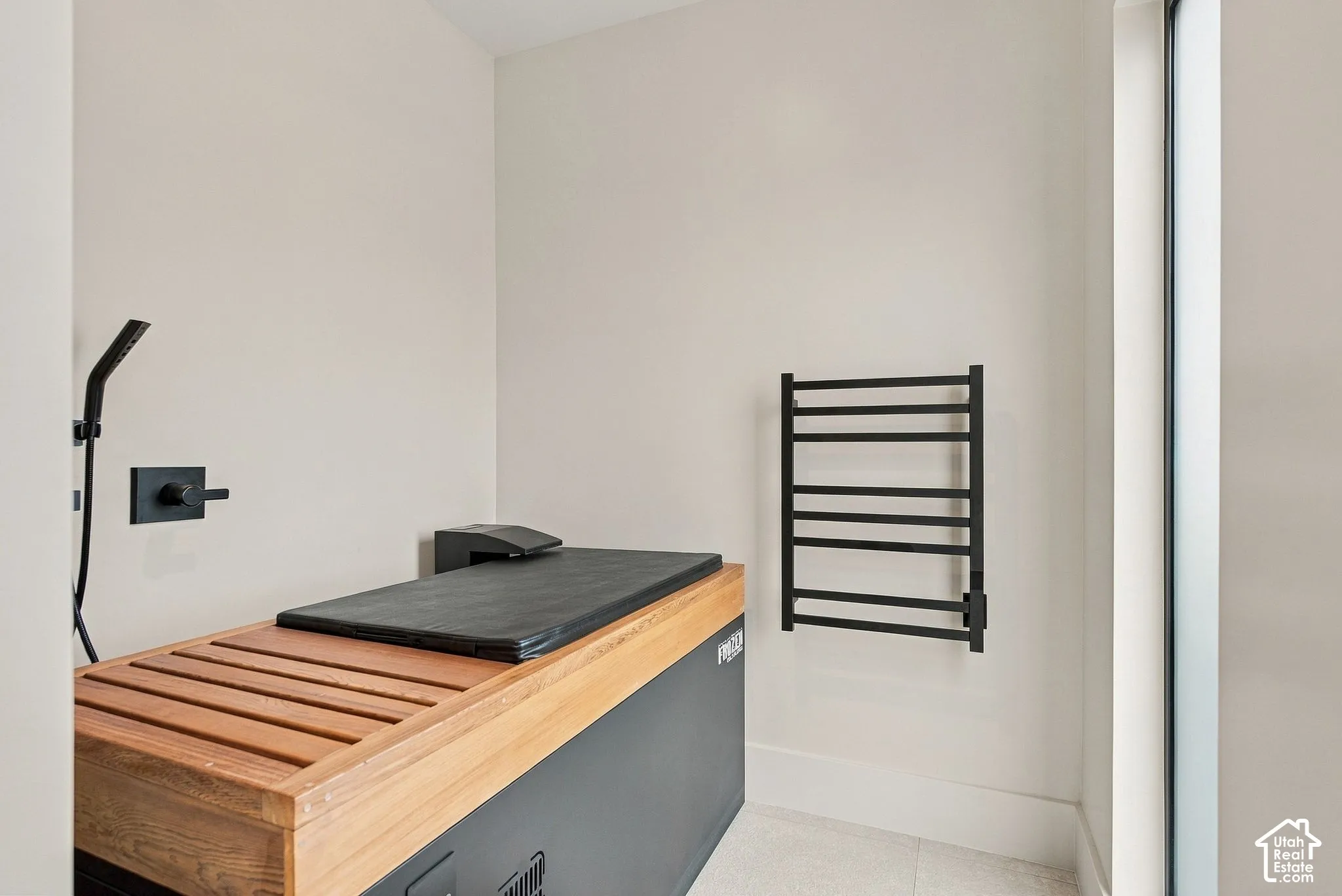 Built-in sauna featuring a slatted wood bench top, matte black wall-mounted towel warmer, and integrated matte black shower fixture
