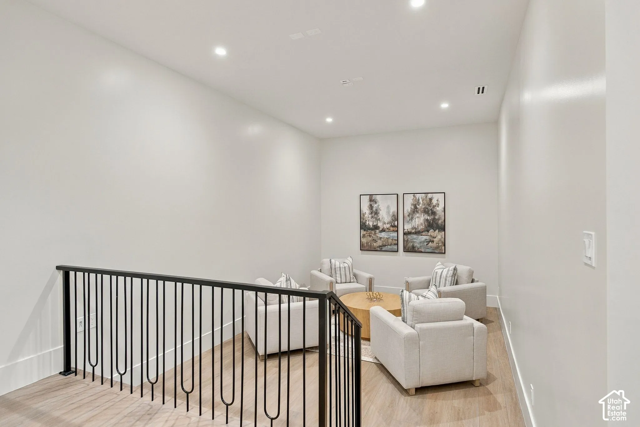 Open interior space featuring wood-finish flooring, high ceilings, recessed lighting, and a black metal spindle railing
