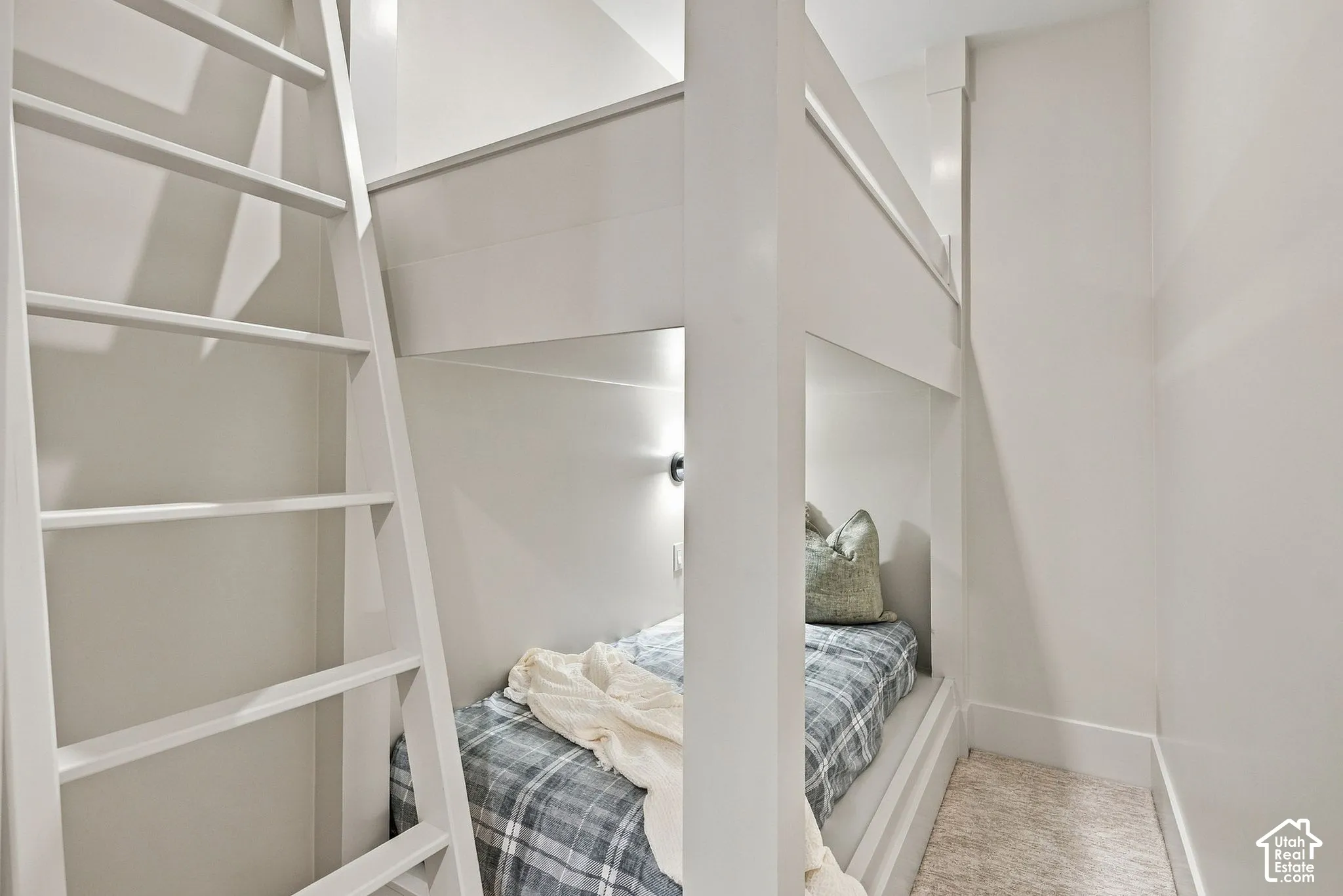 Custom built-in white bunk bed structure featuring a fixed vertical ladder and integrated wall-mounted lighting