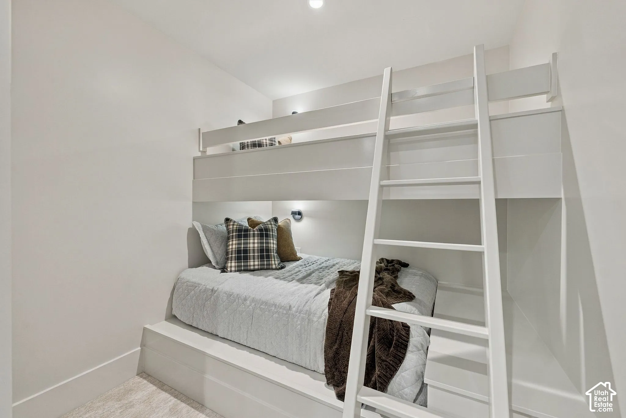 Built-in white platform bunk structure featuring integrated ladder and recessed accent lighting
