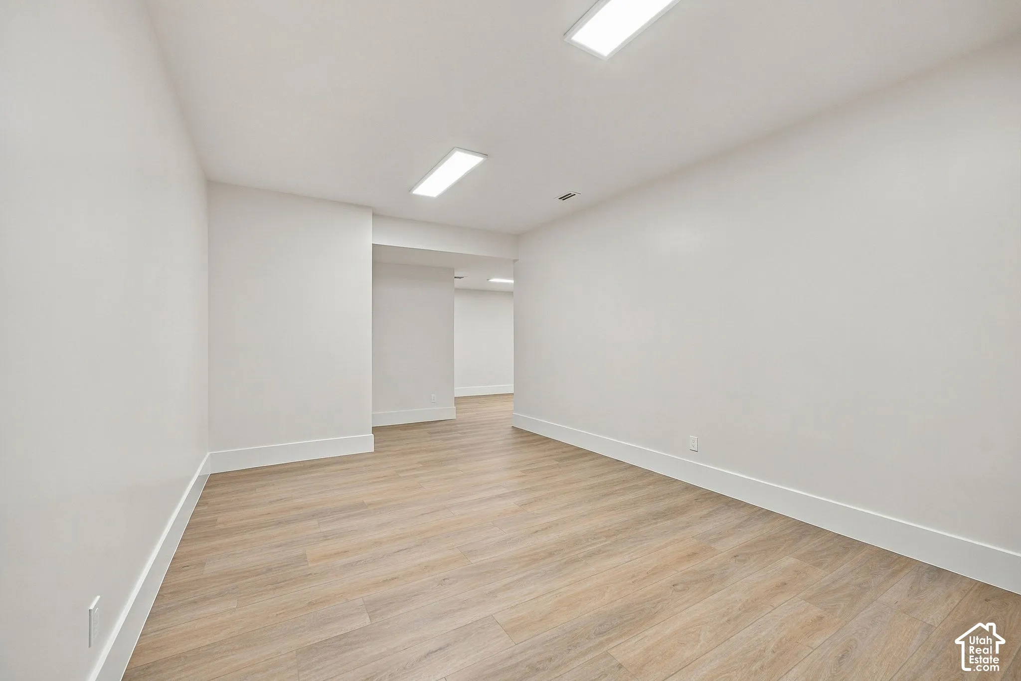 Neutral-toned interior featuring wood-finish flooring, smooth-finish walls, and recessed rectangular lighting