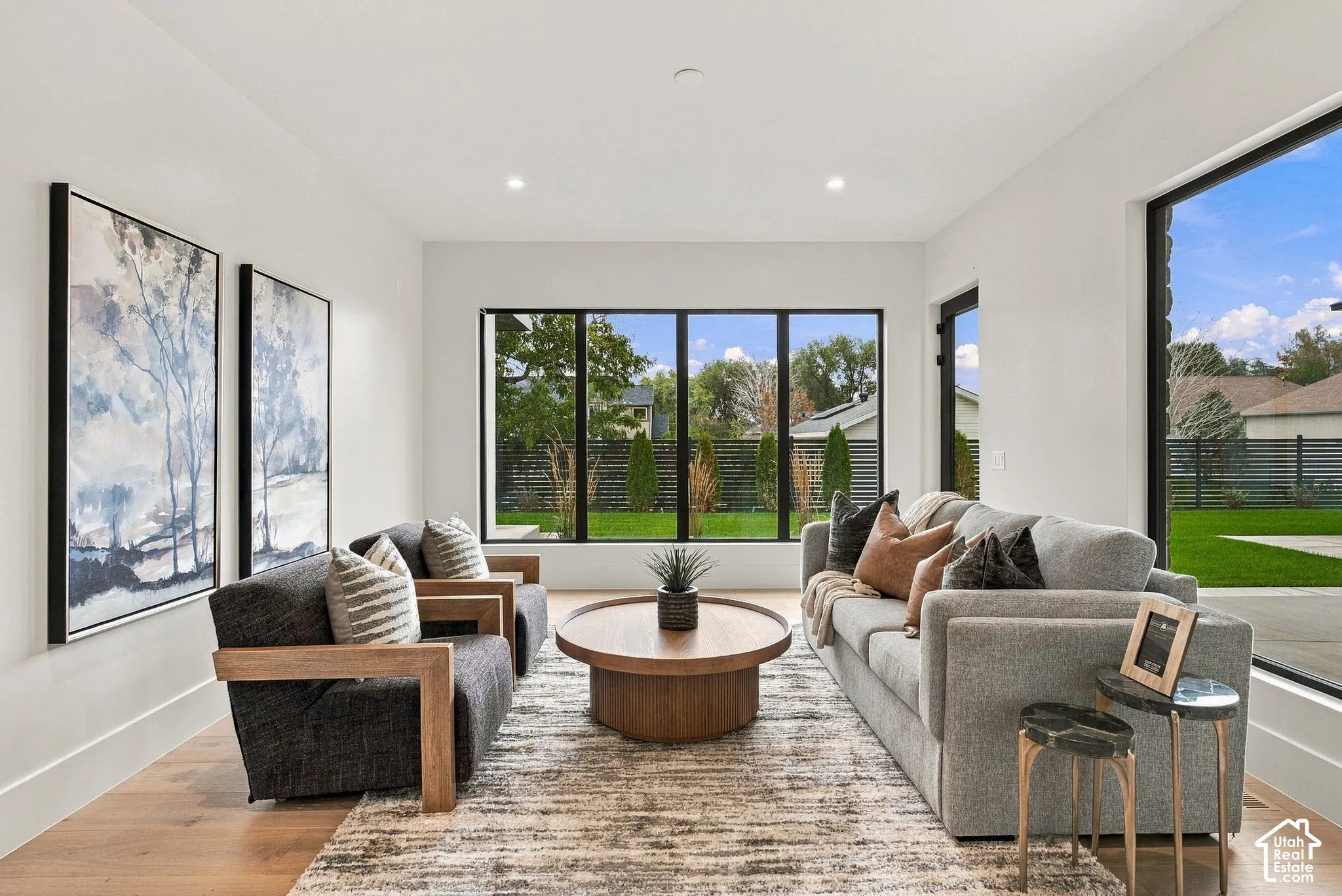 Open-concept interior featuring wood-finish flooring, recessed lighting, and expansive floor-to-ceiling windows with black frames