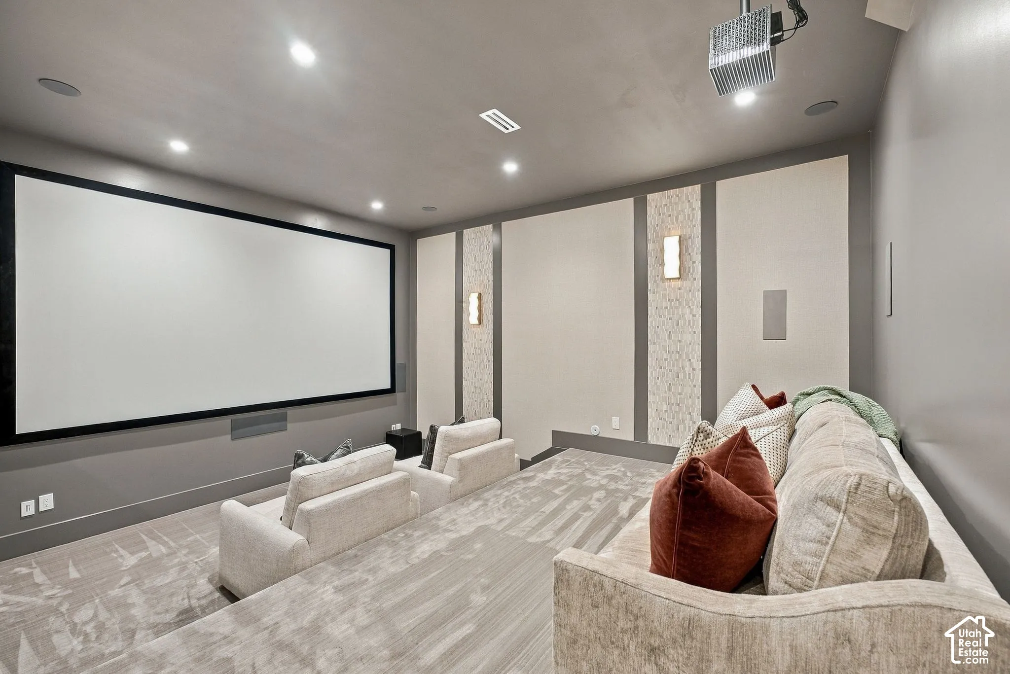 Media room featuring a fixed projection screen, integrated ceiling-mounted projector, wall-mounted accent lighting, and custom wall paneling with textured inserts
