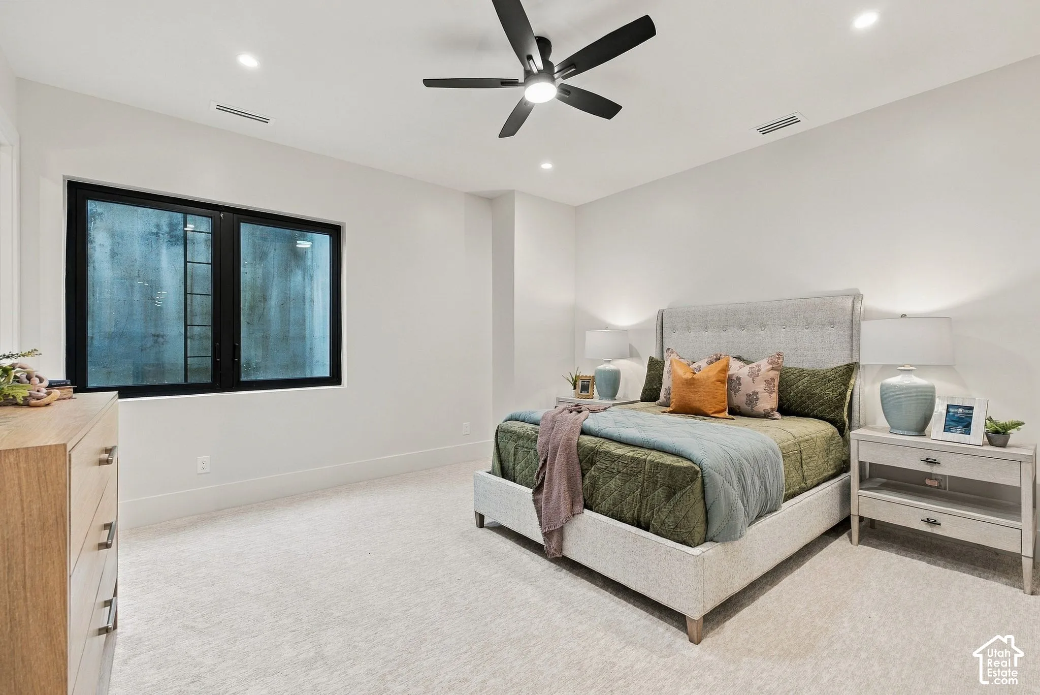 Neutral-toned carpeted flooring, recessed lighting, matte black window frames, and an integrated ceiling fan with light fixture