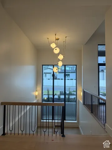 Two-story entry with a contemporary chandelier, large picture windows, wood-finish flooring, and black metal railings with wood handrails