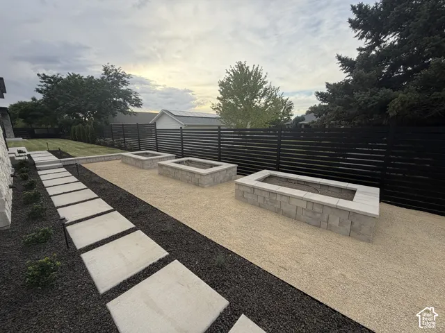 Outdoor living space featuring three built-in garden beds, a modern slatted black fence, and a stone paver walkway