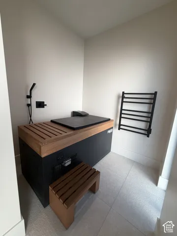 Built-in cold plunge with natural wood accents, matte black wall-mounted shower fixture, and a coordinating wood-slat step
