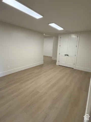 Open-concept interior space featuring light wood-finish flooring, white walls, and white baseboards