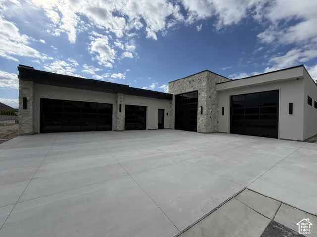 14 ft RV garage, 12 ft garage, expansive 3 car garage featuring multiple glass-paneled, tinted garage doors, stone accents, and a spacious concrete driveway