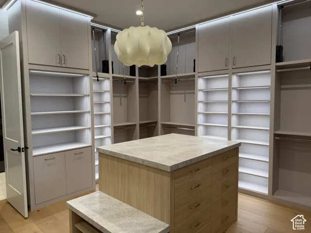 Primary custom closet system featuring built-in shelving, integrated lighting, and a central island with a stone-finish countertop