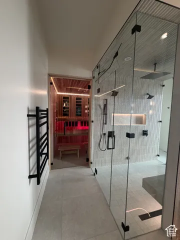 Spa-inspired bathroom featuring a glass-enclosed shower with multiple showerheads, a built-in bench, and textured wall tiling