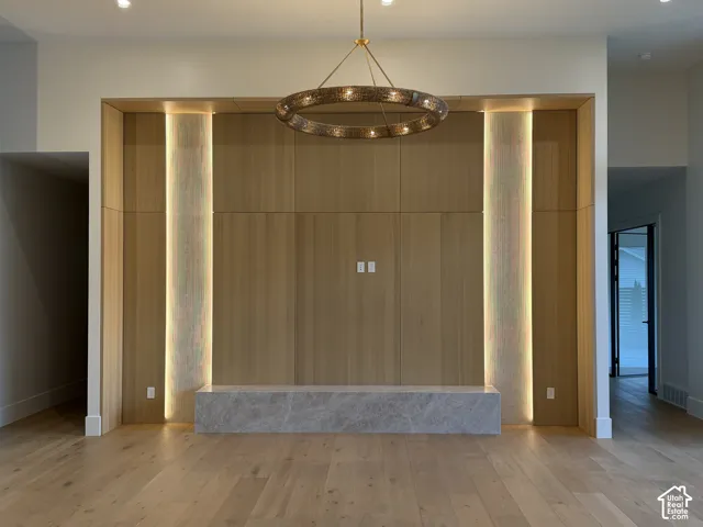 Integrated wood-paneled wall unit with ambient backlighting, Taj Mahal stone hearth, and a brass-toned chandelier