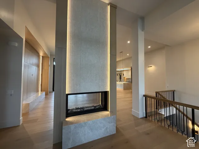 Modern double sided fireplace designed with stone and wood, with a linear glass-enclosed firebox and integrated vertical accent lighting