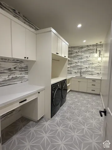 Spacious utility room featuring patterned floor tiling, extensive built-in cabinetry with matte black hardware, white quartz countertops, and modern pendant lighting