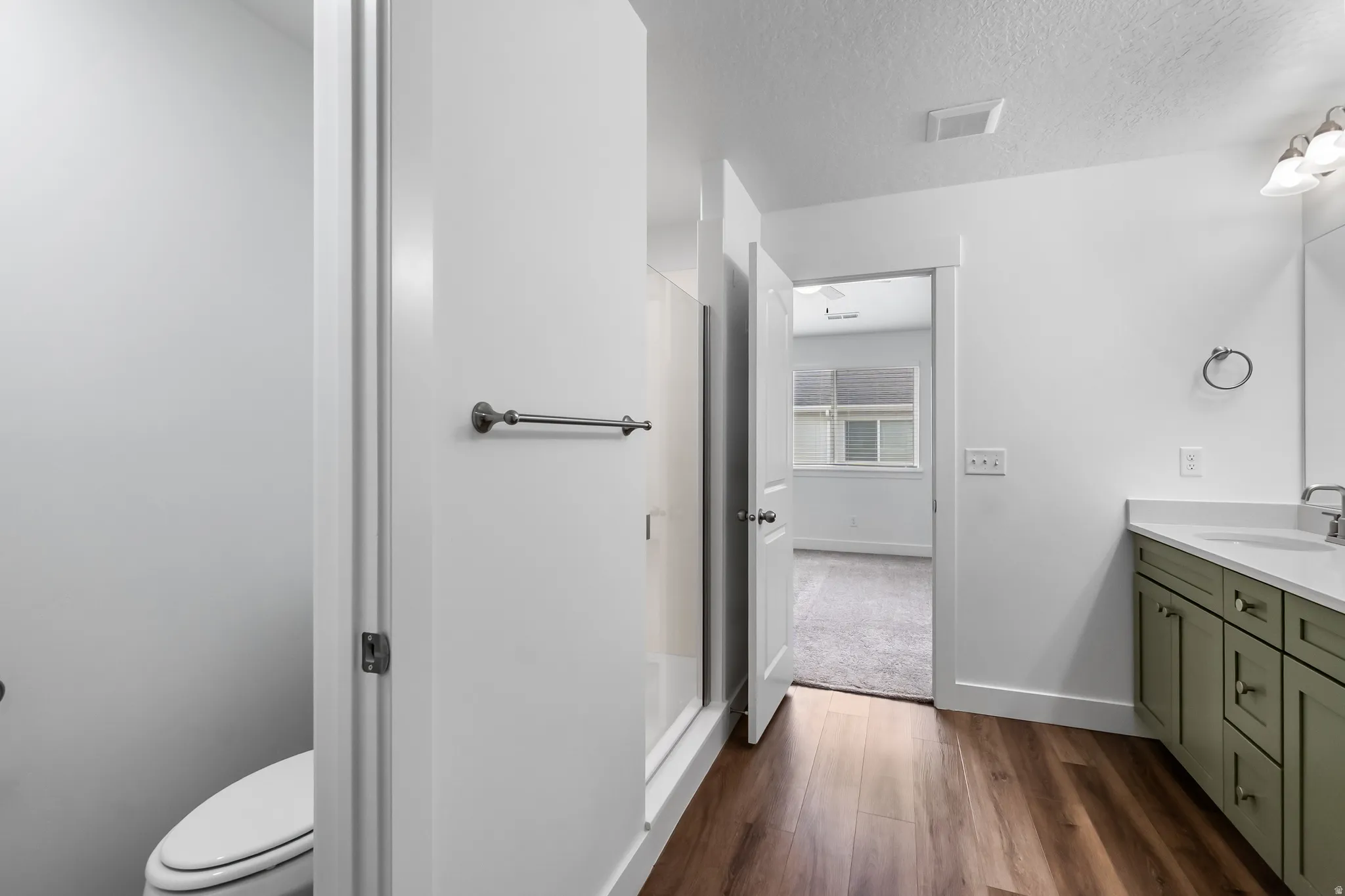 Bathroom with vanity, dark wood-type flooring, a textured ceiling, and a stall shower