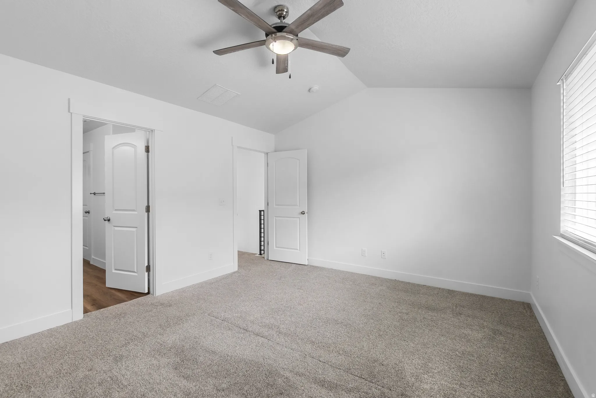 Unfurnished bedroom with carpet, vaulted ceiling, and ceiling fan