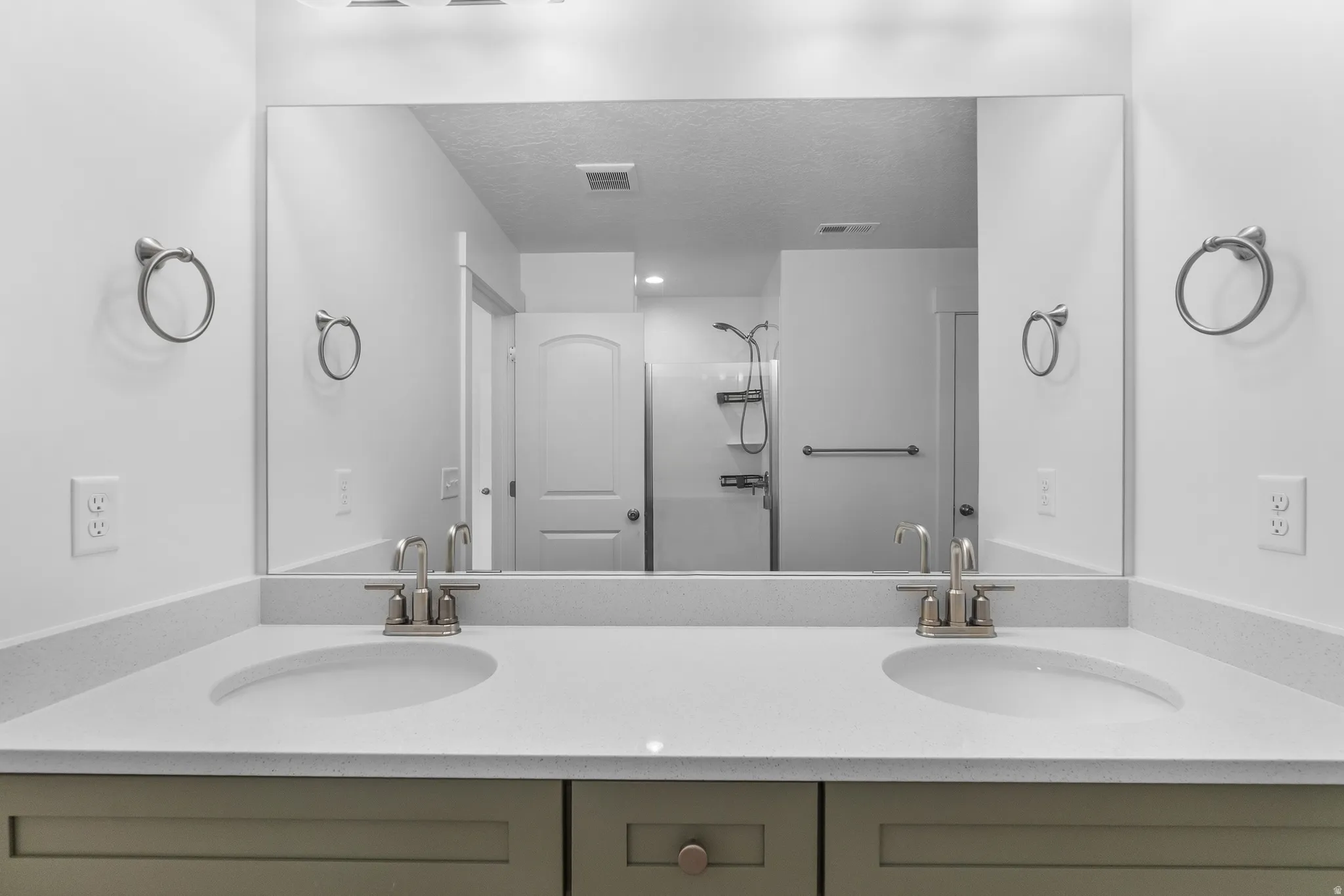 Bathroom with double vanity, a stall shower, and a textured ceiling