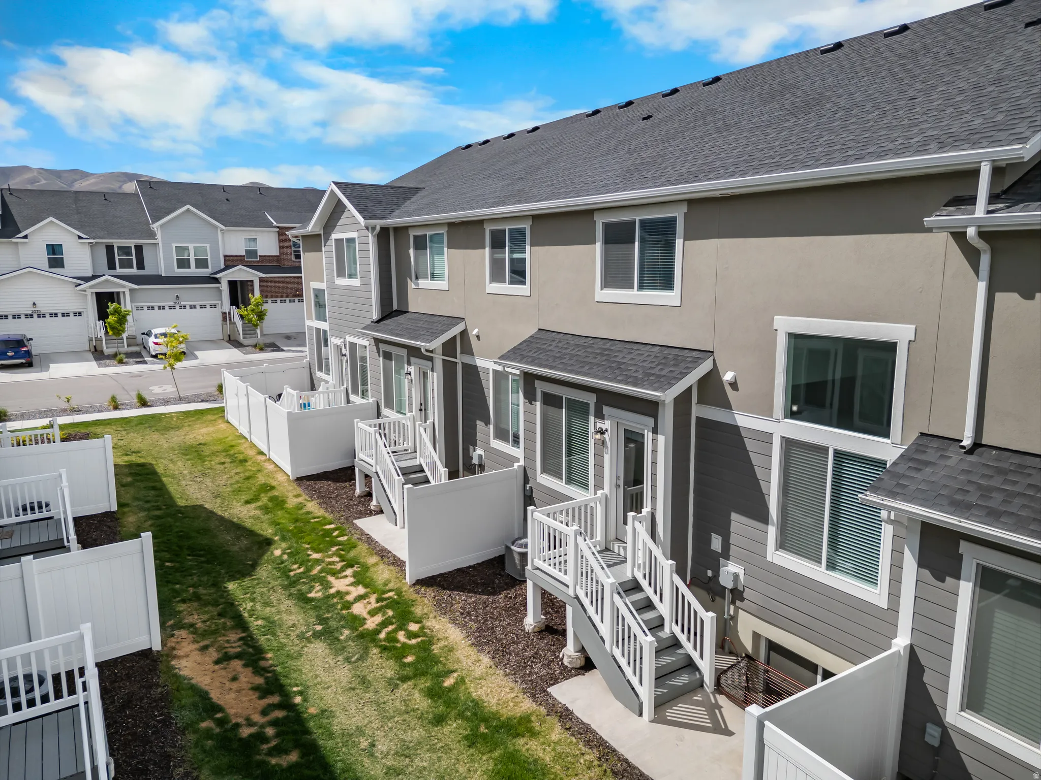 Rear view of property featuring a shingled roof, stucco siding, a residential view, and a patio