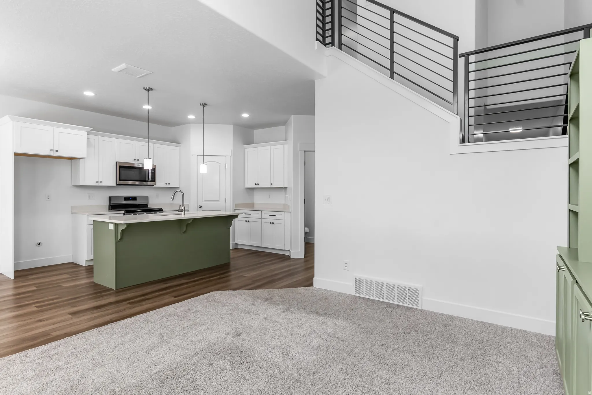 Dual tone kitchen featuring a kitchen breakfast bar, stainless steel appliances, a kitchen island with sink, two tone cabinetry, and dark colored carpet