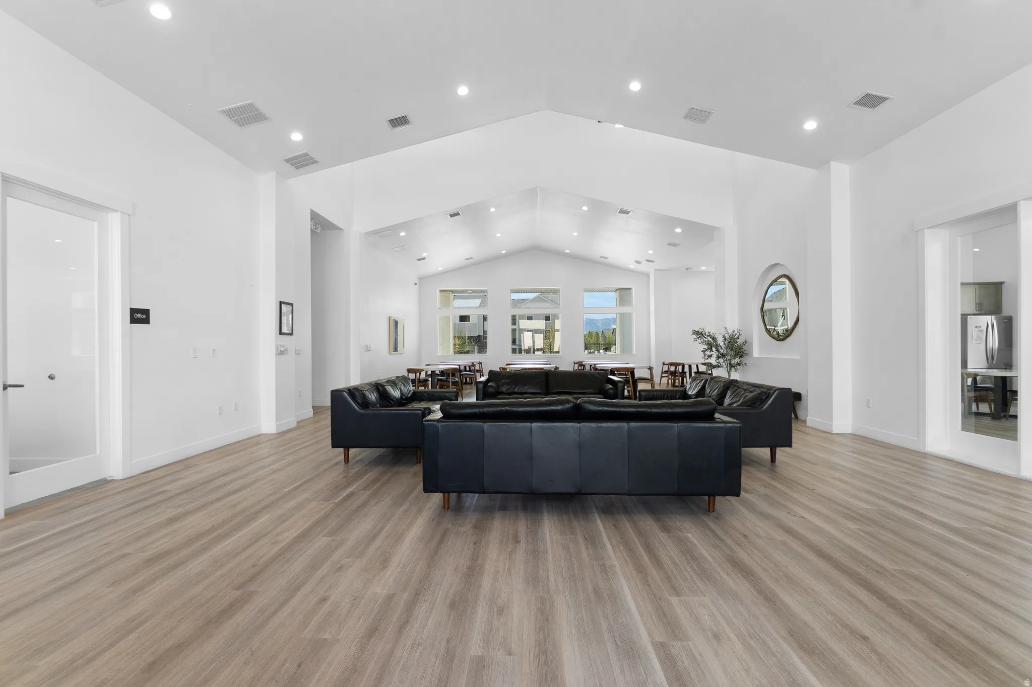 Living area with light wood finished floors, recessed lighting, and a high ceiling