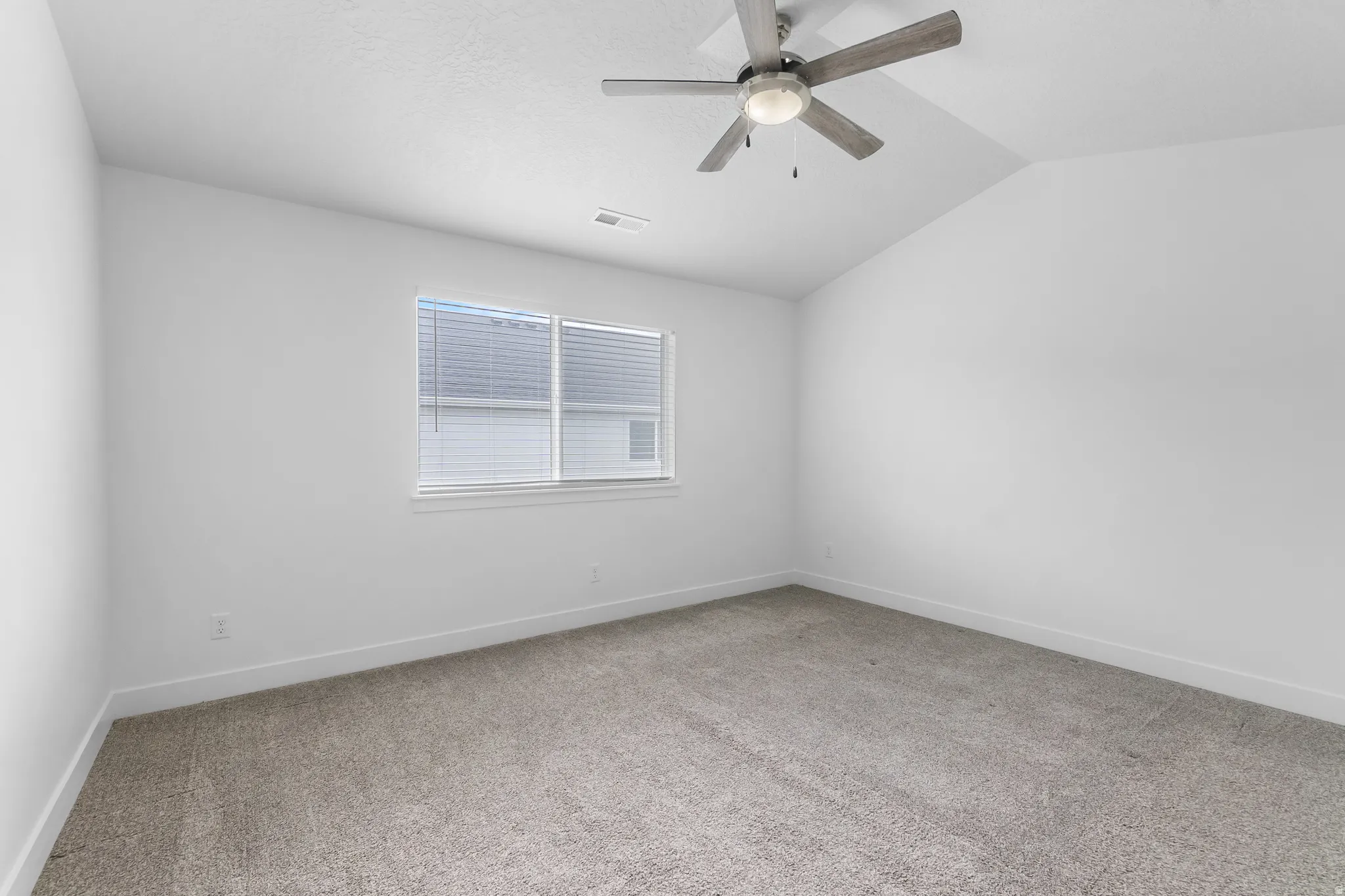 Unfurnished room with ceiling fan, light carpet, and vaulted ceiling