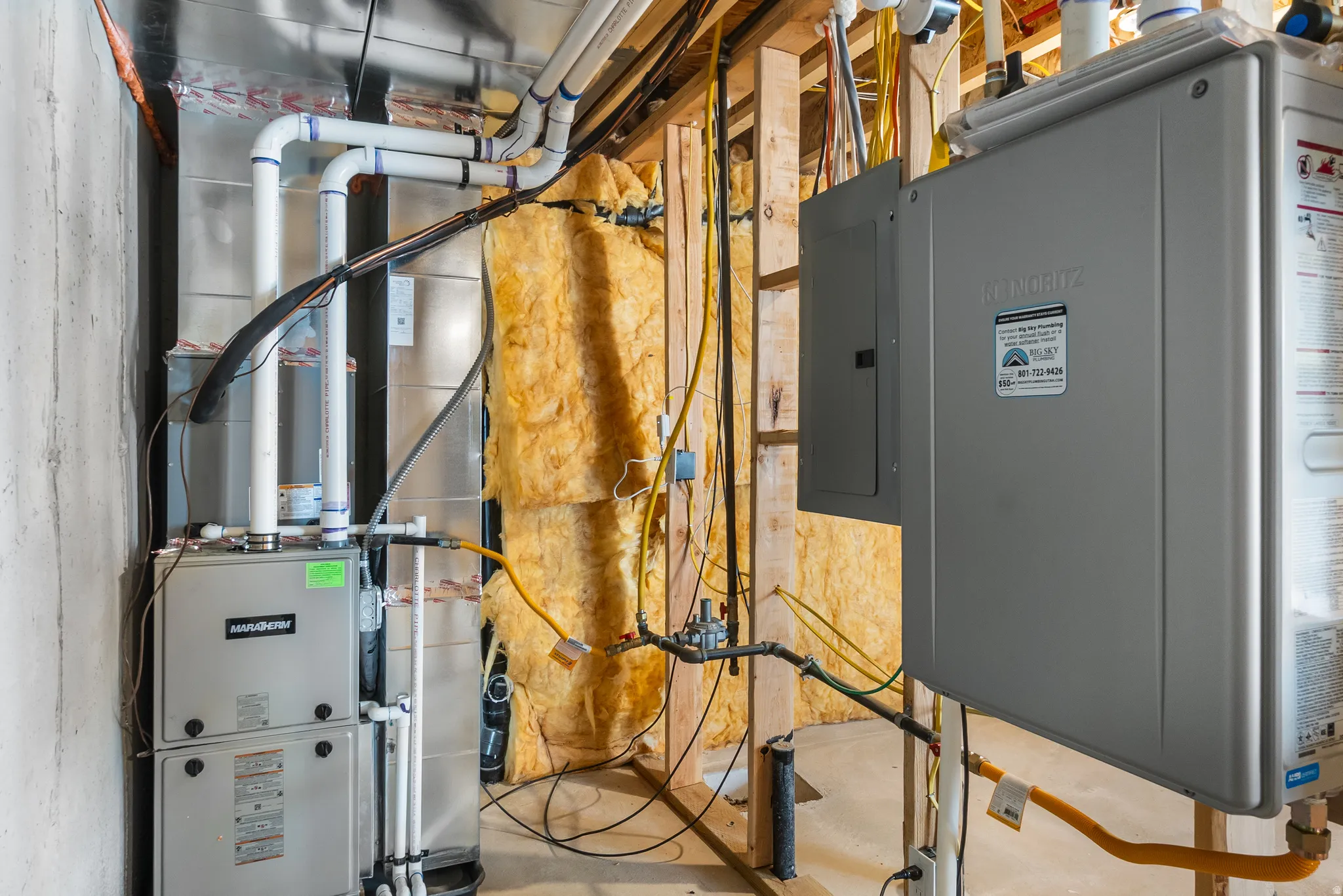Utility room featuring electric panel, heating unit, and water heater