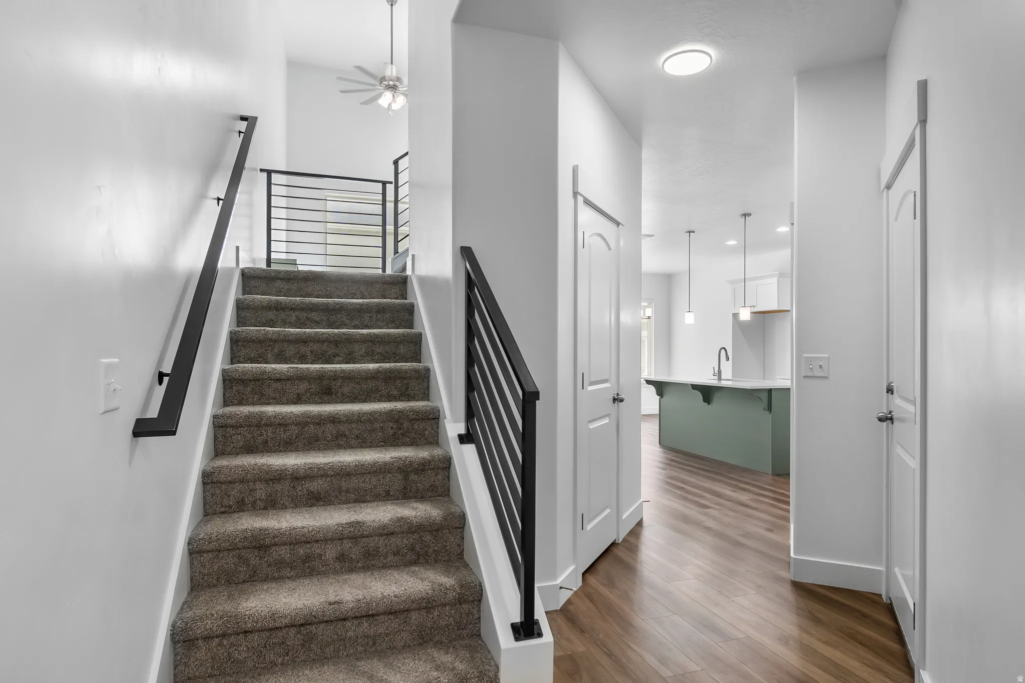 Stairs with wood finished floors and ceiling fan