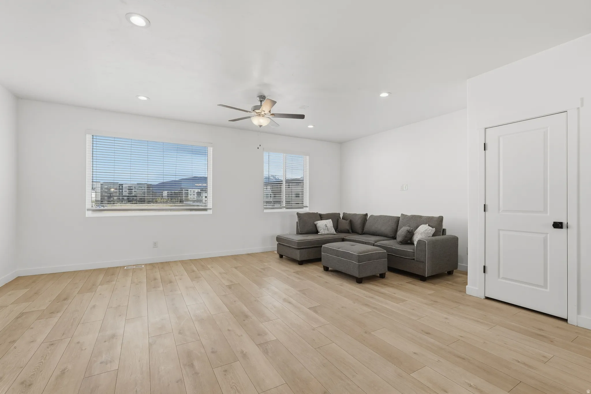 Living area with a ceiling fan, light wood-style flooring, and recessed lighting