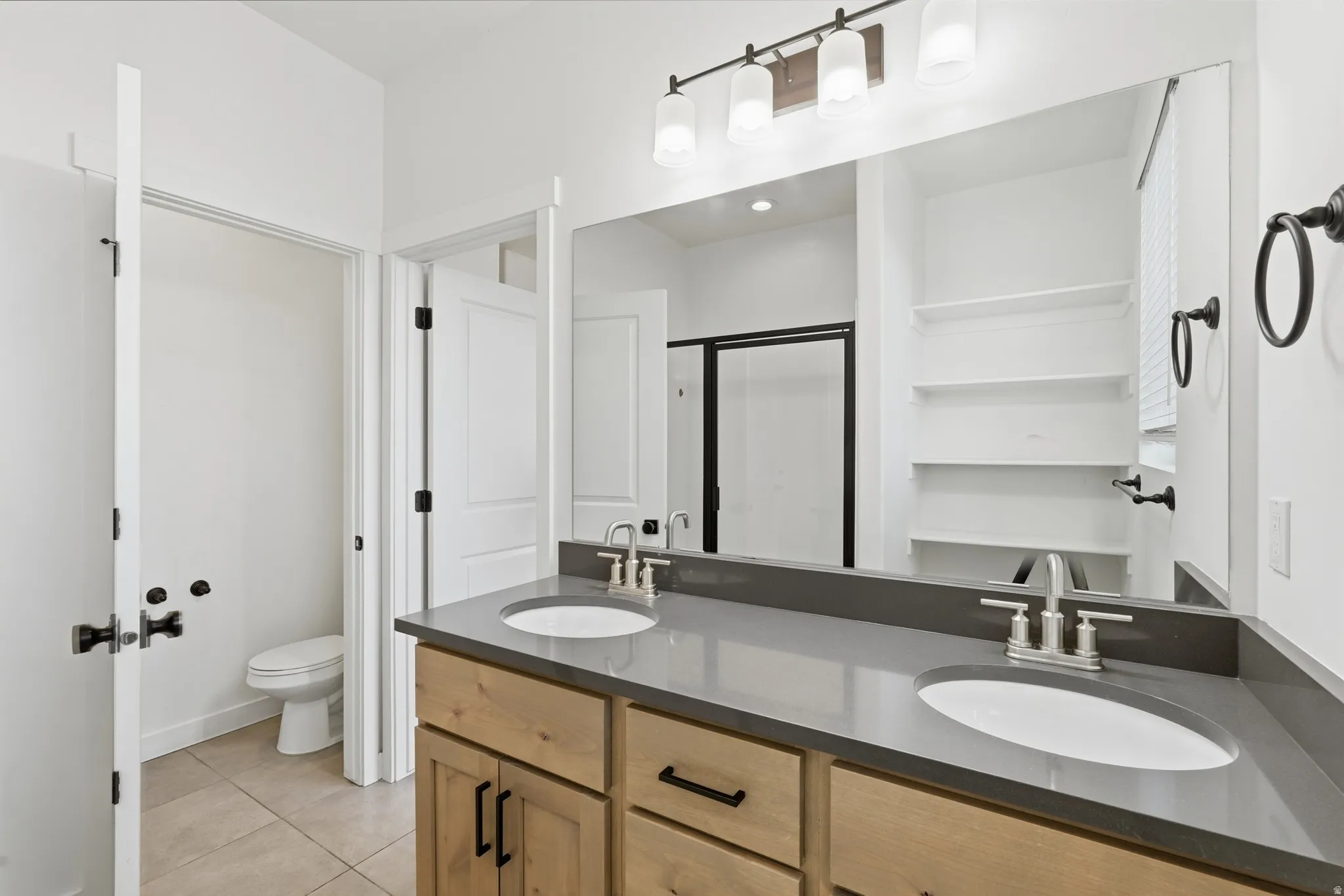 Full bath with double vanity, a stall shower, and light tile patterned floors