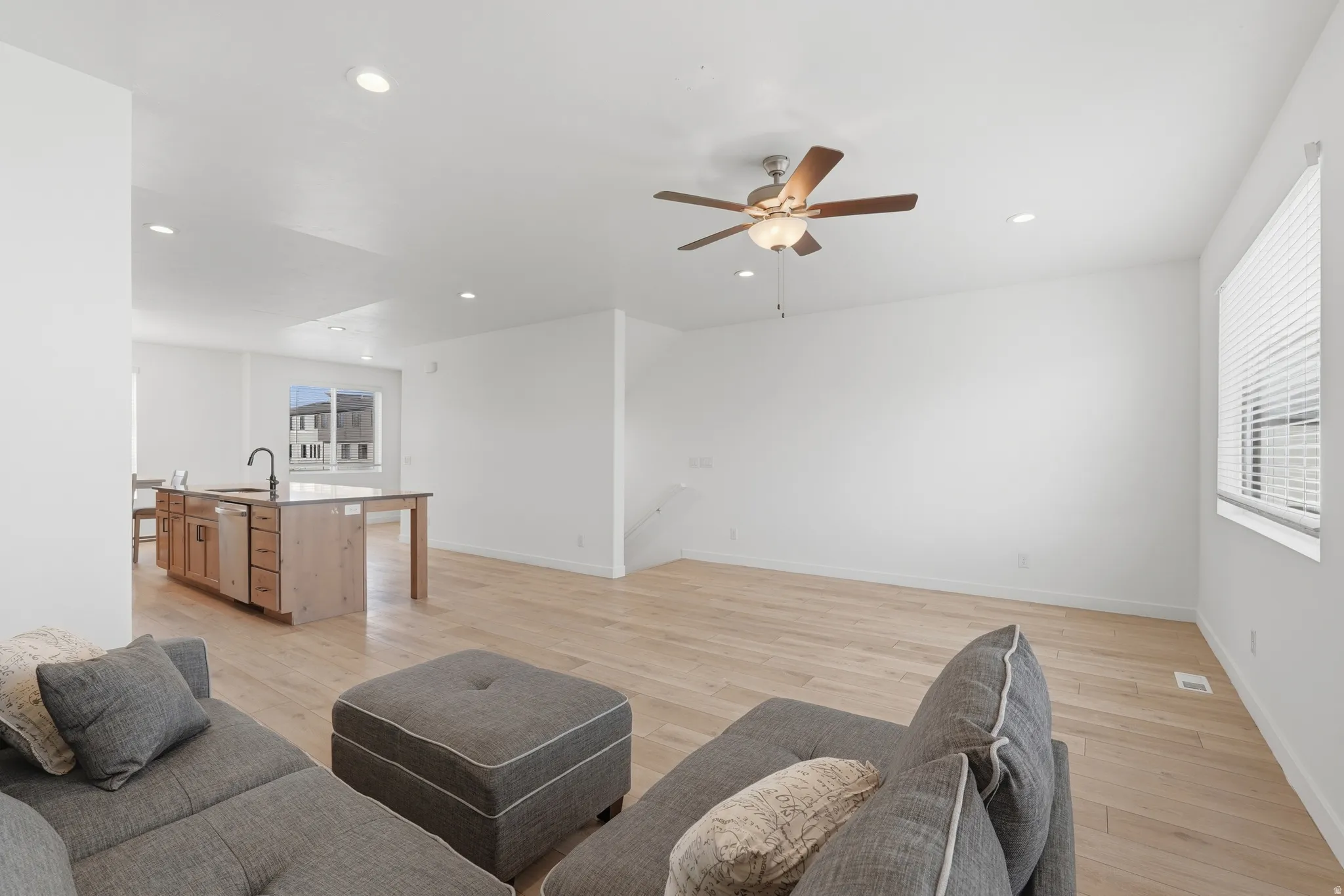 Living area featuring light wood finished floors, a ceiling fan, and recessed lighting