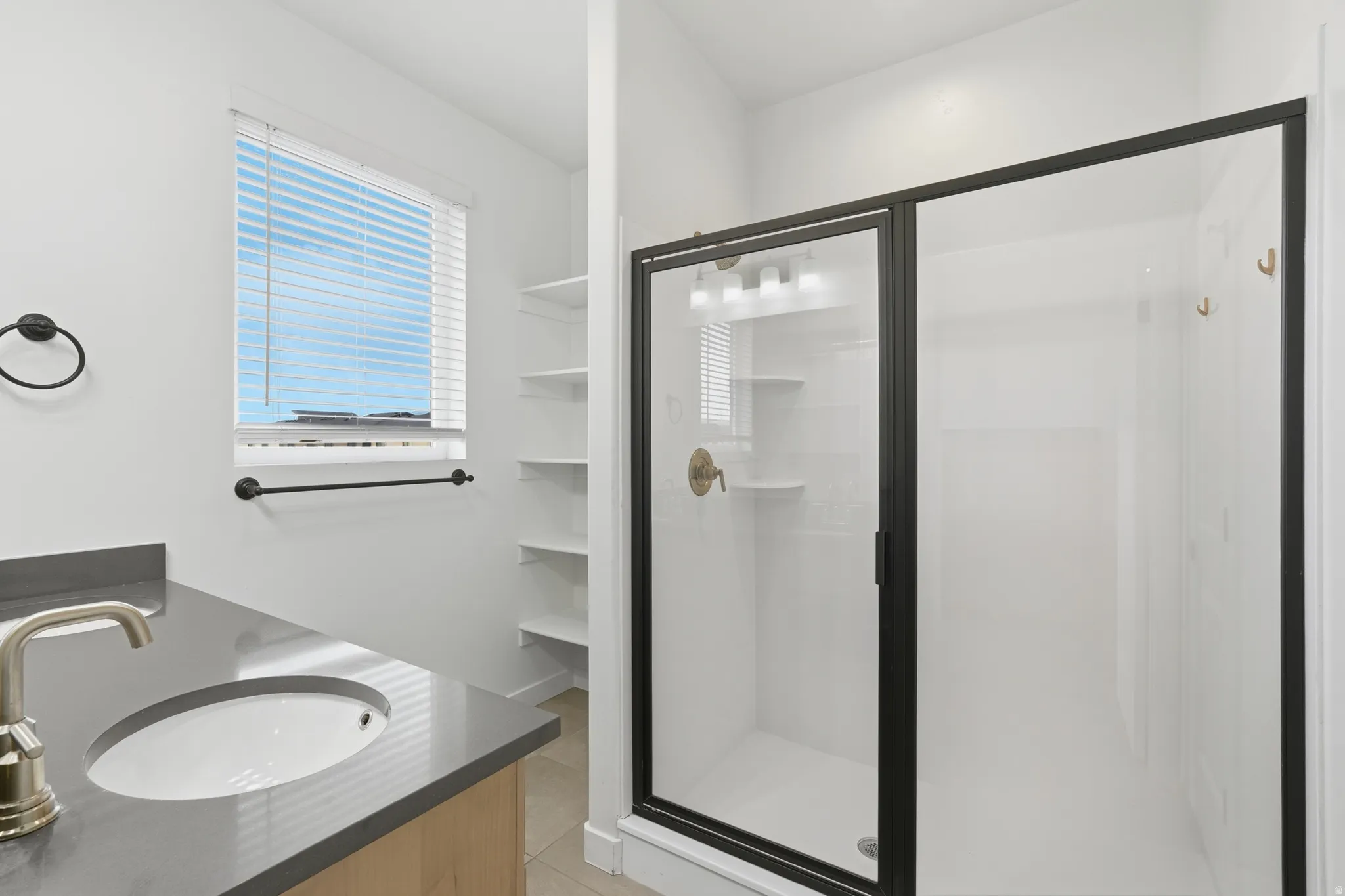 Full bathroom featuring double vanity, a stall shower, and light tile patterned floors