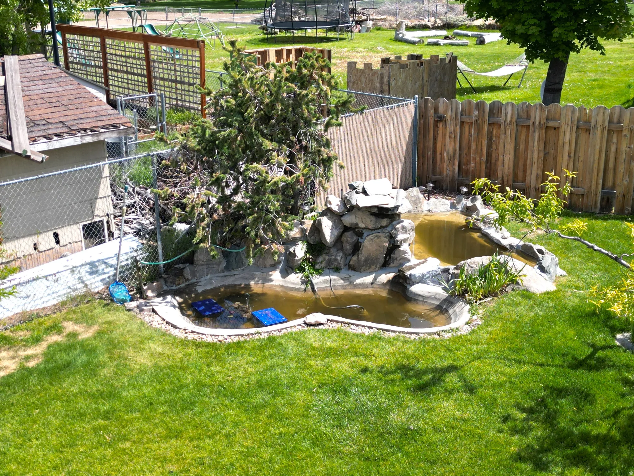 Fenced backyard with a small pond with a waterfall