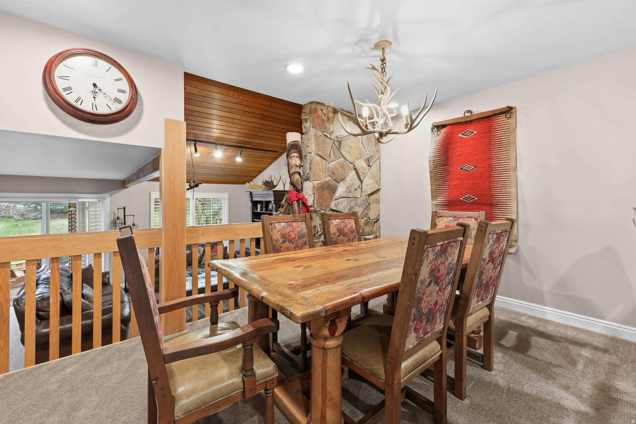 Dining space featuring carpet flooring, suspended lighting, and a vaulted wooden ceiling