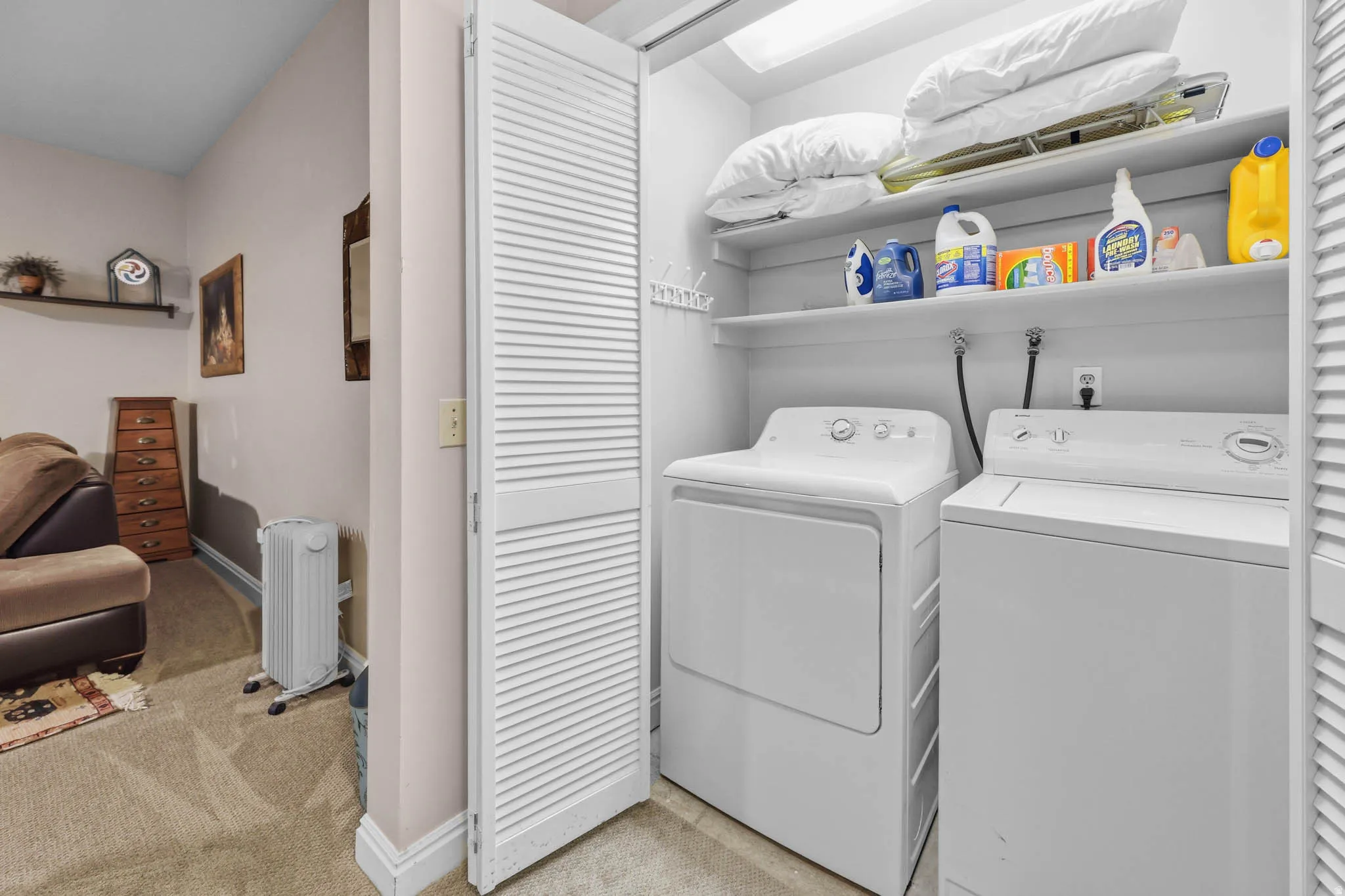 Laundry area with radiator, light colored carpet, and washer and dryer