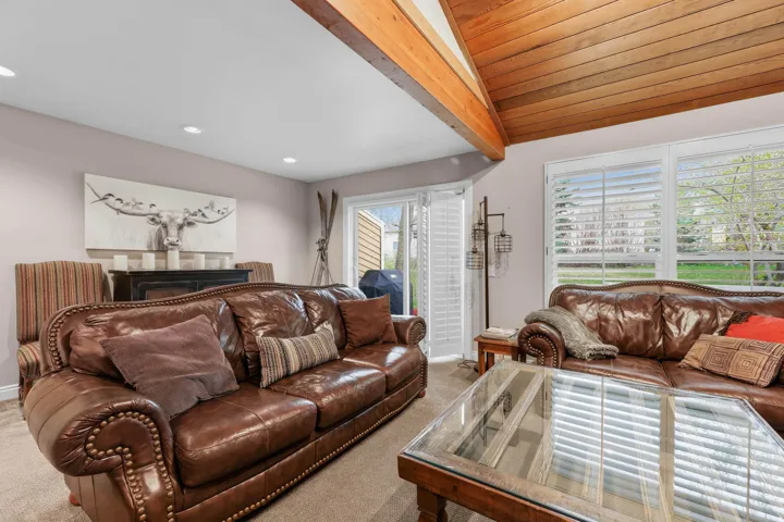 Carpeted living room with recessed lighting and beamed ceiling