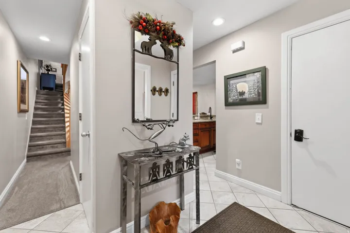 Hall with light tile patterned floors, recessed lighting, and light colored carpet