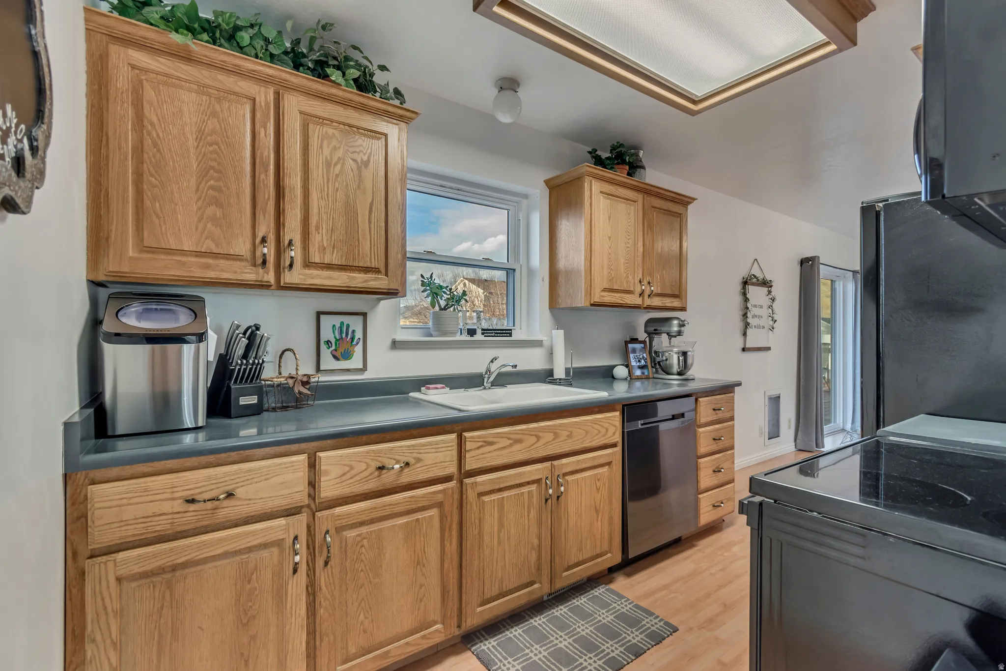 Kitchen with dark countertops, stainless steel appliances, light wood-style floors, and wood finish cabinetry