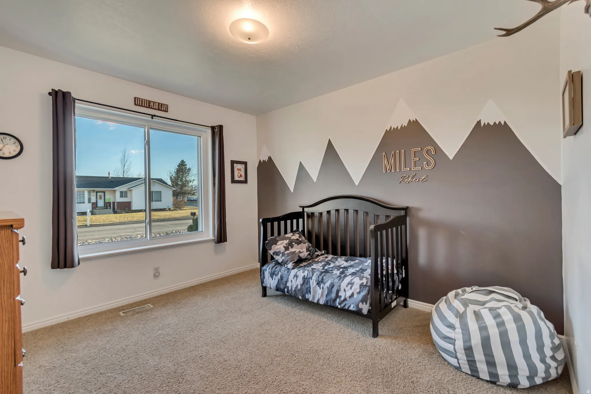 Carpeted bedroom with baseboards and a crib