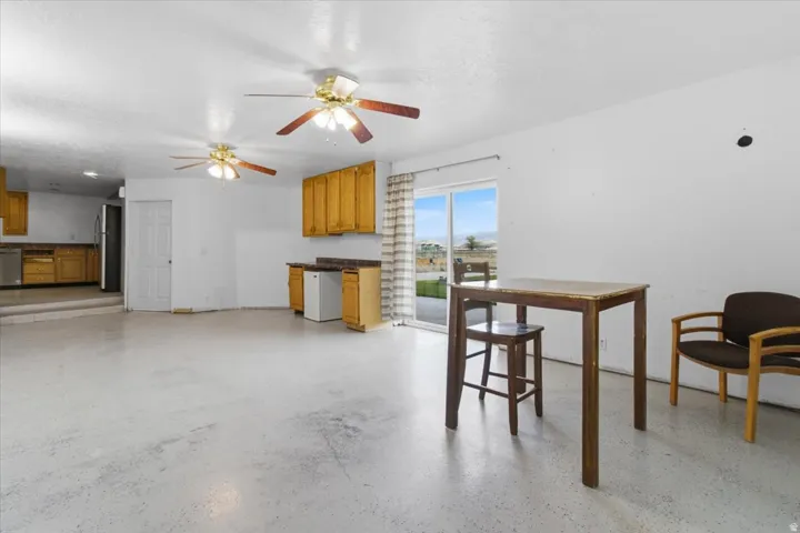 Kitchen featuring wood finish cabinets, stainless steel appliances, ceiling fan, dark countertops, and a textured ceiling
