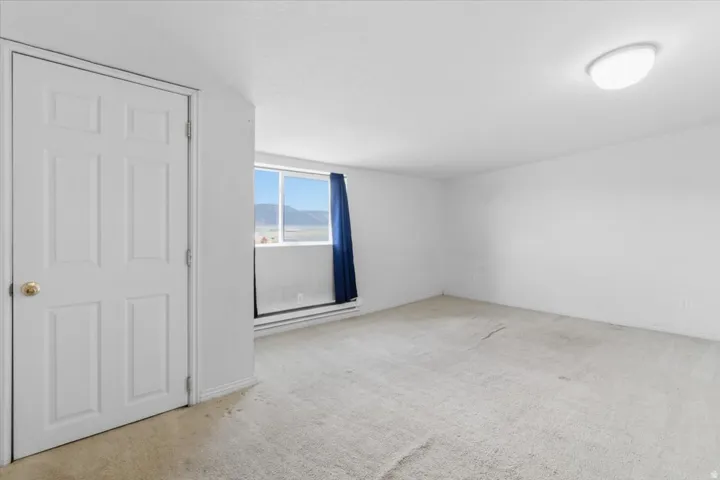 Unfurnished room with light carpet and baseboard heating