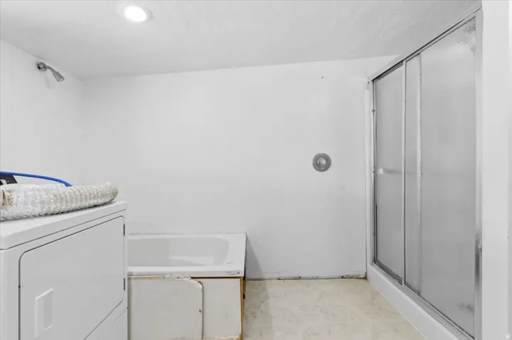 Bathroom featuring washer / clothes dryer, a stall shower, a textured ceiling, and vanity