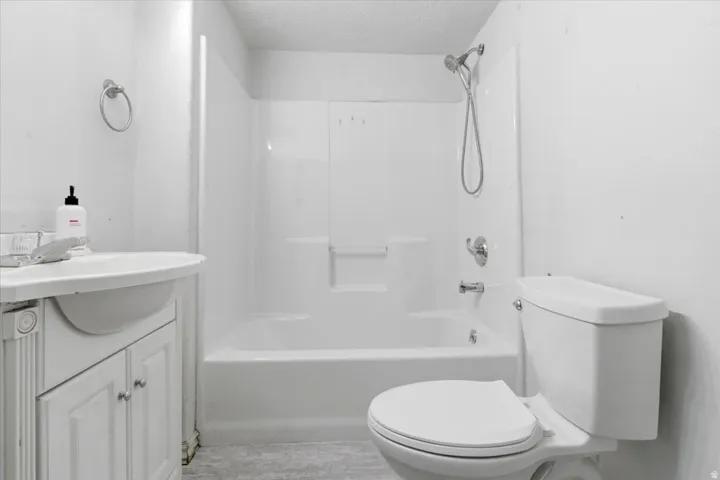 Bathroom featuring vanity, a textured ceiling, and bathing tub / shower combination