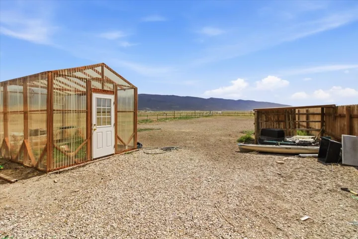 View of yard featuring an exterior structure, an outdoor structure, a mountain view, and a view of countryside